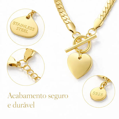 Close do colar dourado com pingente de coração e fecho toggle, mostrando brilho e acabamento do aço inoxidável.