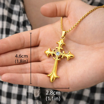 Colar Cruz Áurea™ dourado com pingente de cruz em aço inoxidável apoiado na mão, mostrando tamanho real de 4,6 cm por 2,8 cm e acabamento premium
