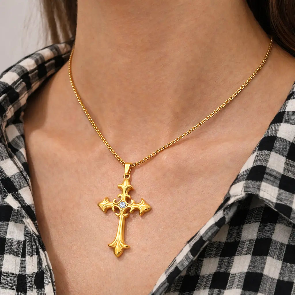 Colar Cruz Áurea™ dourado com pingente de cruz em aço inoxidável sendo usado no pescoço feminino em look casual, joia versátil para o dia a dia