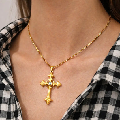 Colar Cruz Áurea™ dourado com pingente de cruz em aço inoxidável sendo usado no pescoço feminino em look casual, joia versátil para o dia a dia