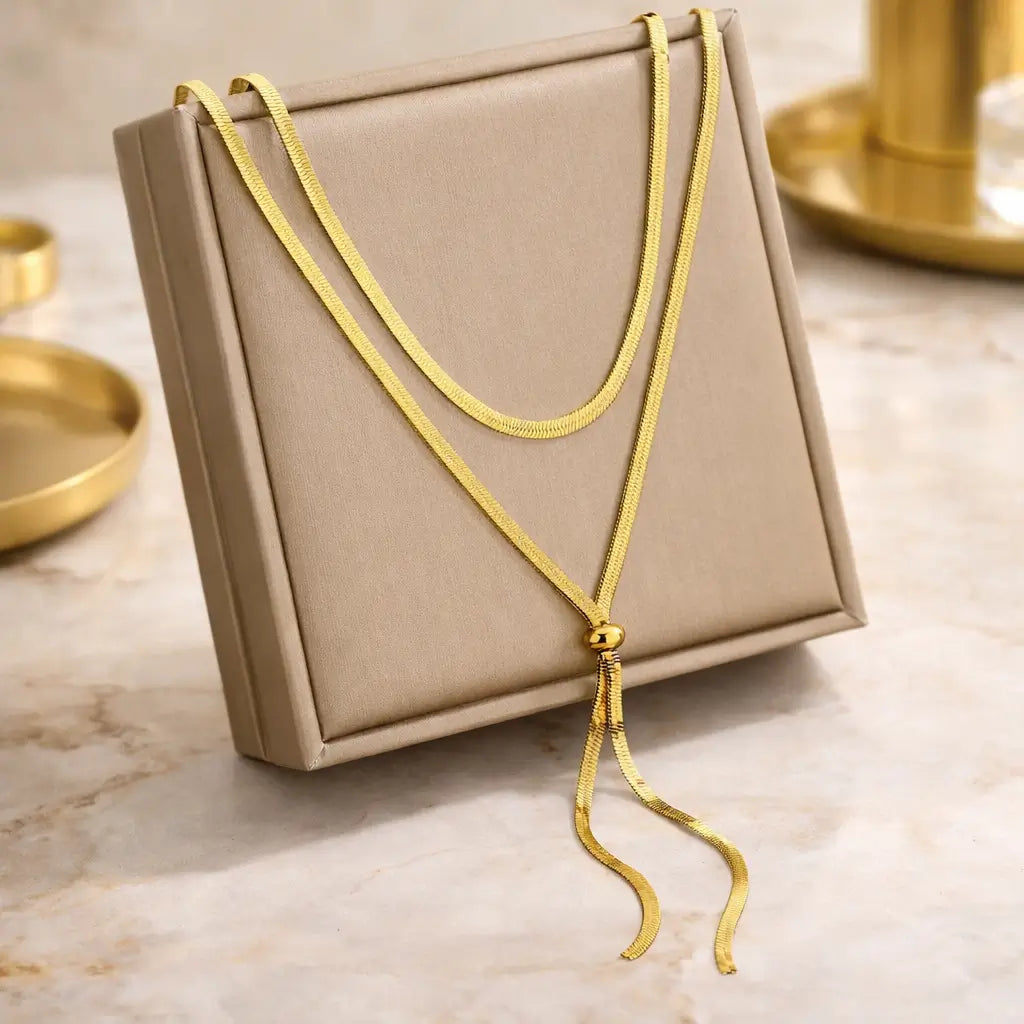 Colar Dourado Aura Linear™ em aço inoxidável ajustável com cursor deslizante, permitindo regulagem de comprimento e caimento em formato Y