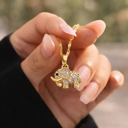 Colar feminino dourado com pingente de elefante cravejado em zircônia segurado na mão, mostrando tamanho real, delicadeza e acabamento premium