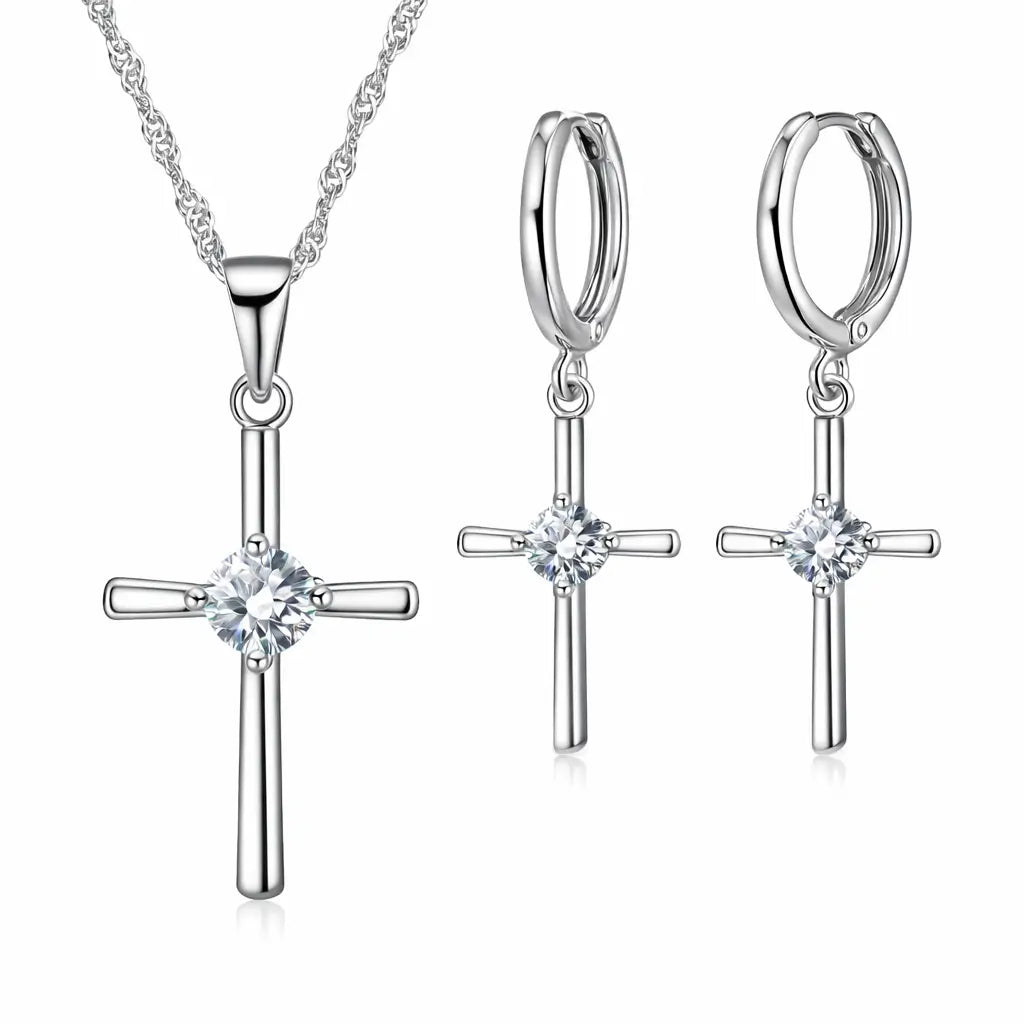 Conjunto Cruz Lumière em Prata 925 com zircônia cristal: colar com pingente de cruz e brincos de cruz em fundo branco.