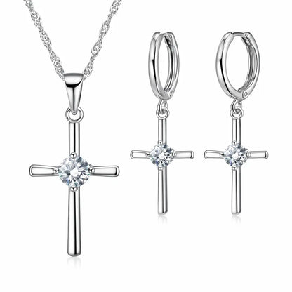 Conjunto Cruz Lumière em Prata 925 com zircônia cristal: colar com pingente de cruz e brincos de cruz em fundo branco.