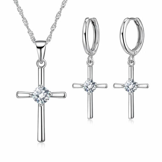 Conjunto Cruz Lumière em Prata 925 com zircônia cristal: colar com pingente de cruz e brincos de cruz em fundo branco.